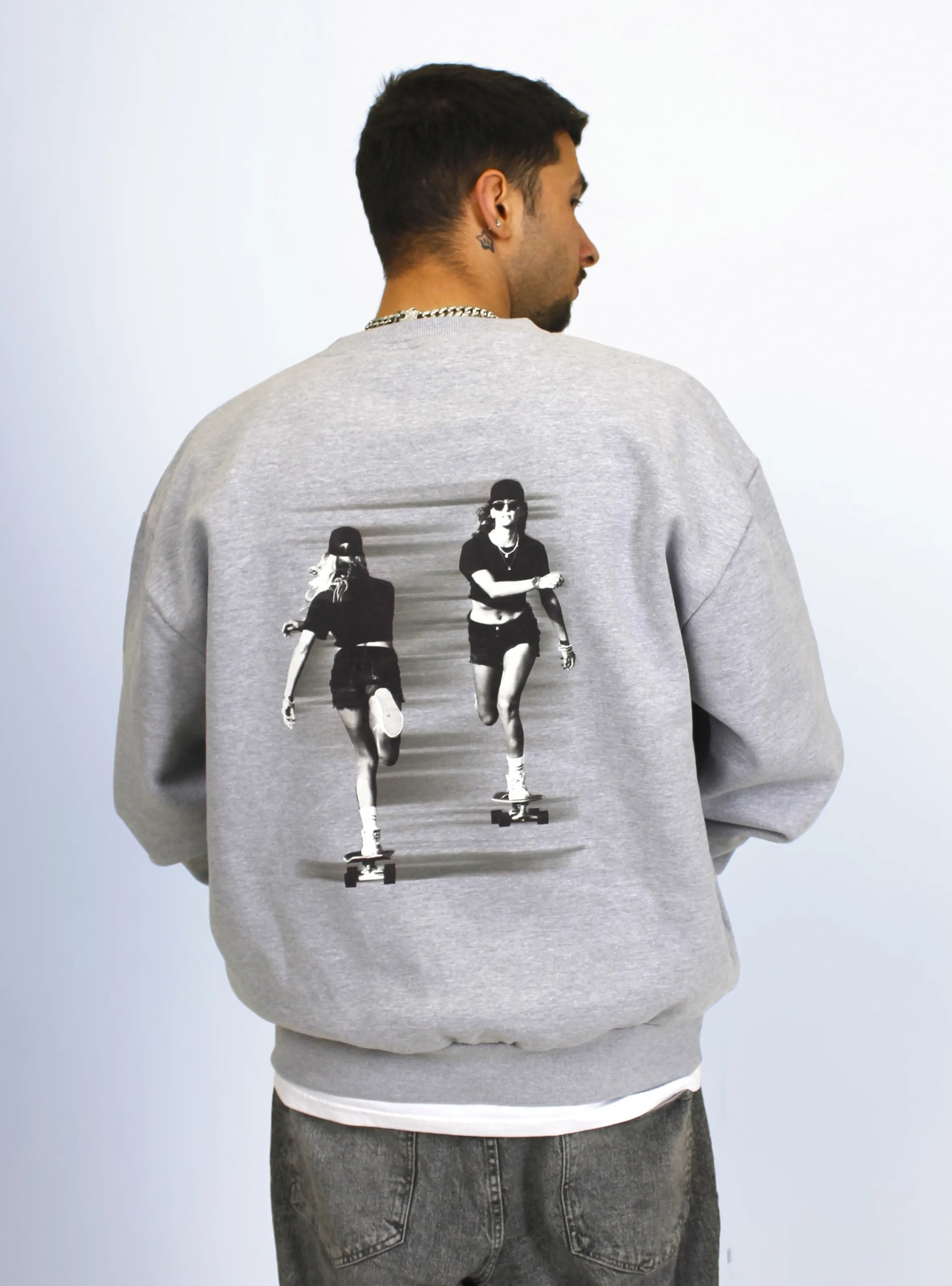 Model wearing grey crewneck sweatshirts with a skater print design at the back.