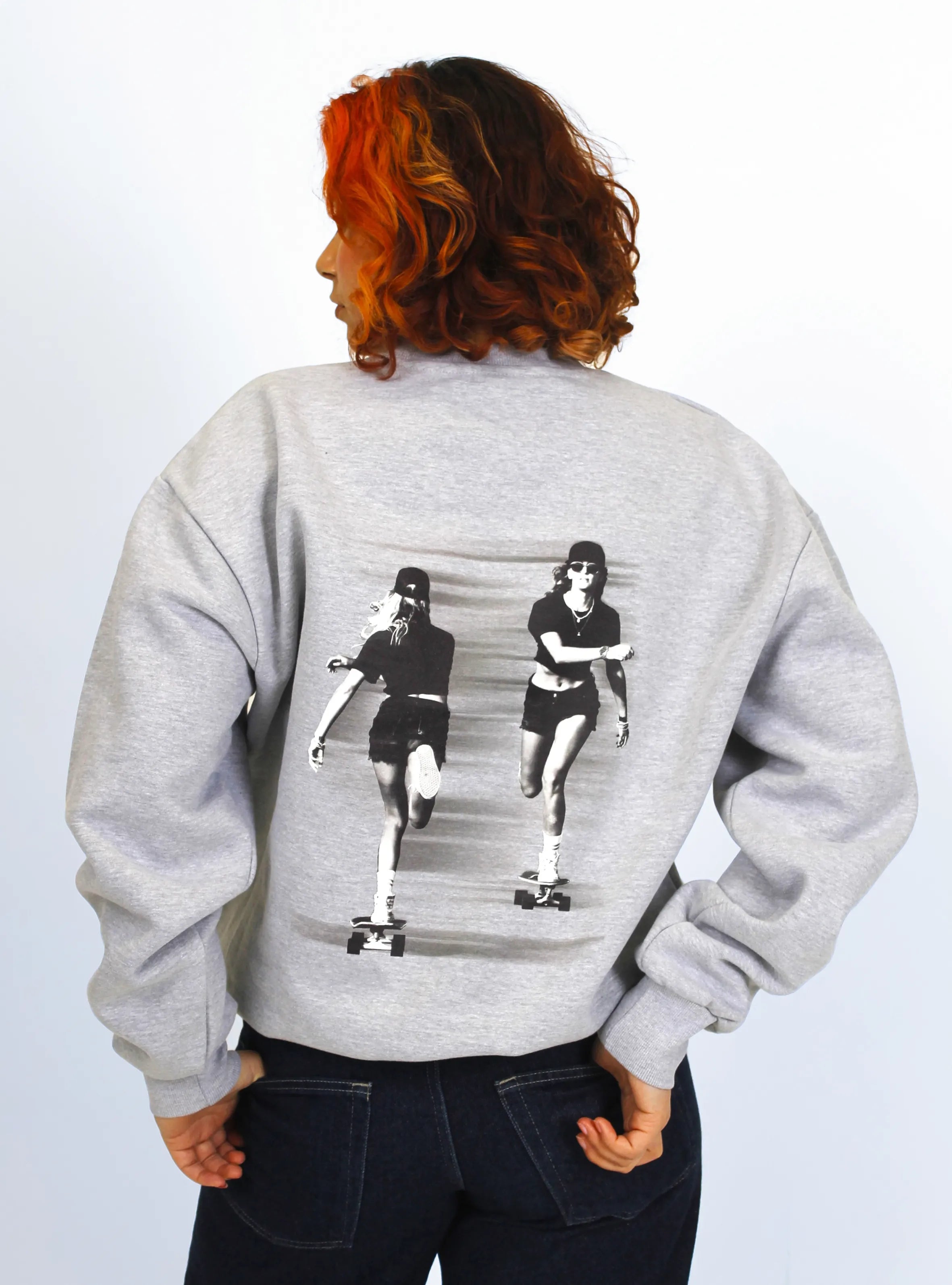 Model wearing grey crewneck sweatshirts with a skater print design at the back.