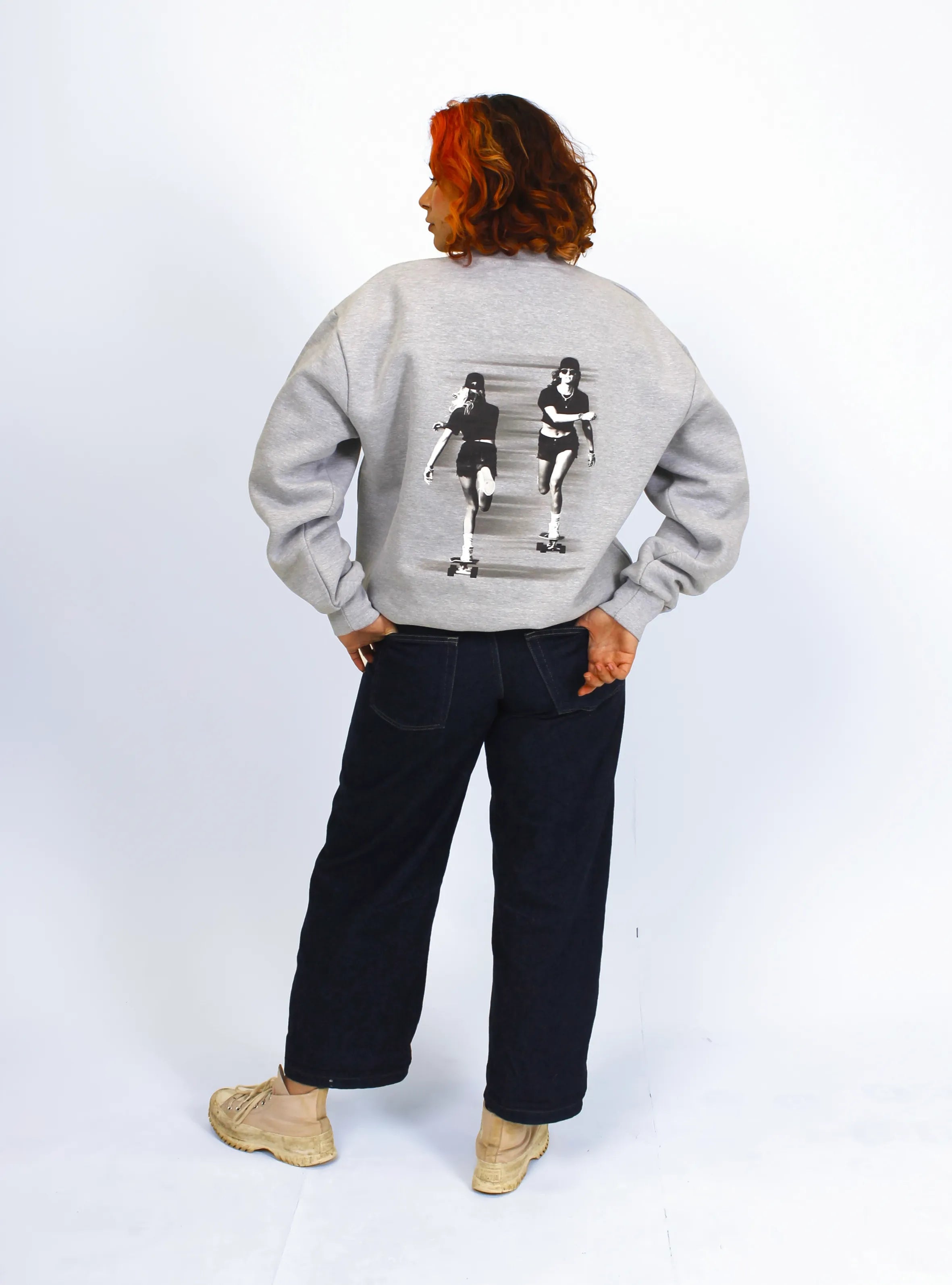 Model wearing grey crewneck sweatshirts with a skater print design at the back.