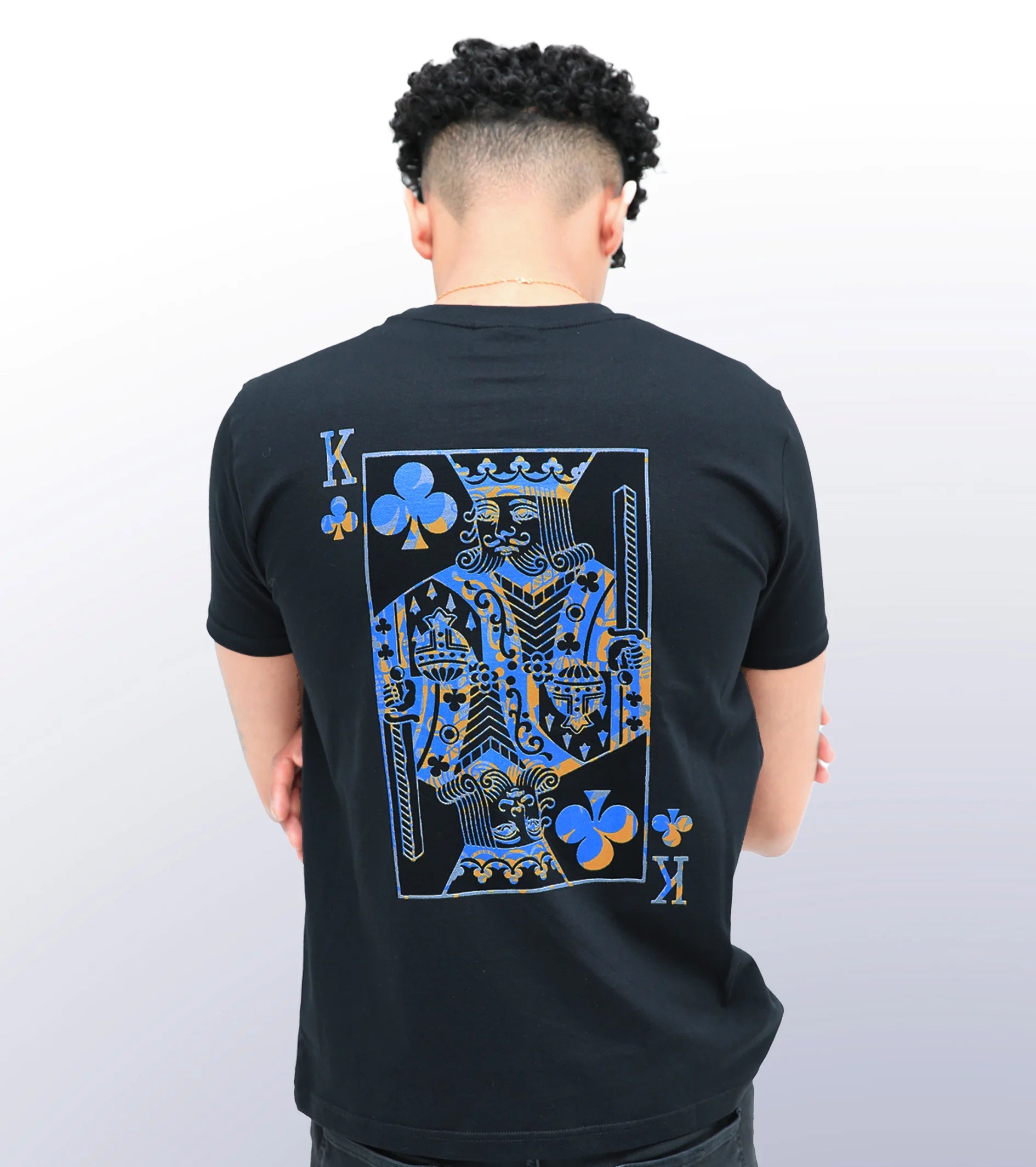 A person wearing a black T-shirt with a print of the King of Clubs playing card in the center back.